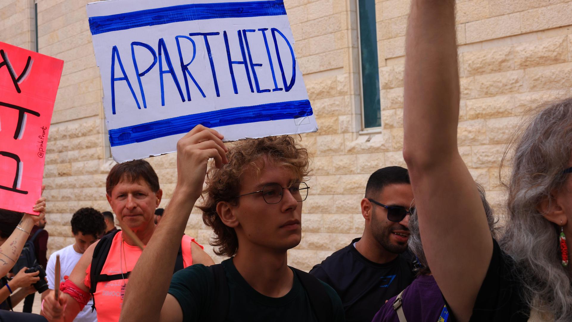 Israelische Aktivisten protestieren, einer hälten ein Schild mit der Aufschrift "Apartheid" hoch Israelische Aktivisten protestieren, einer hälten ein Schild mit der Aufschrift "Apartheid" hoch