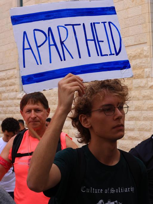 Israelische Aktivisten protestieren, einer hälten ein Schild mit der Aufschrift "Apartheid" hoch Israelische Aktivisten protestieren, einer hälten ein Schild mit der Aufschrift "Apartheid" hoch