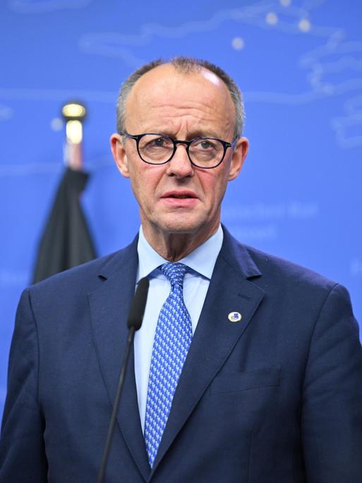 Bundeskanzler Friedrich Merz steht in Anzug und Krawatte vor einem blauen Hintergrund. Bundeskanzler Friedrich Merz steht in Anzug und Krawatte vor einem blauen Hintergrund.