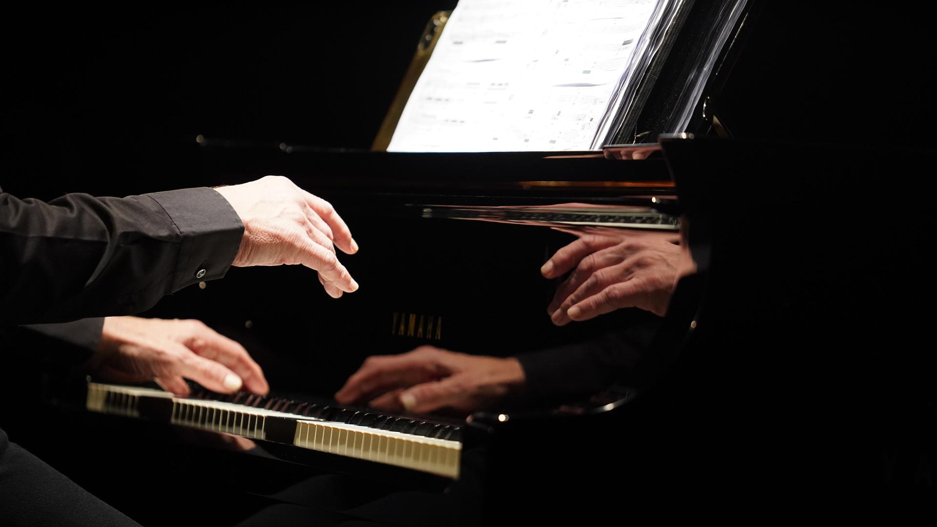 Die Hände des Pianisten spiegeln sich im Korpus eine Flügels