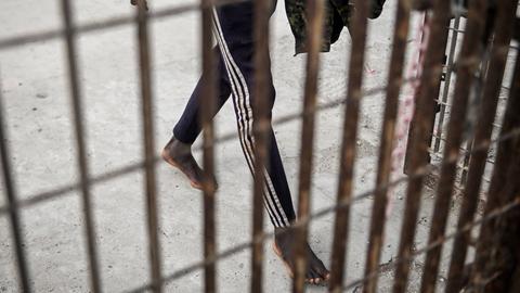 Ein Mann läuft barfuß hinter Gittern