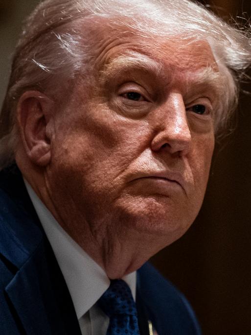 US-Präsident Donald Trump blickt in die Kamera vor einem schwarzen Hintergrund