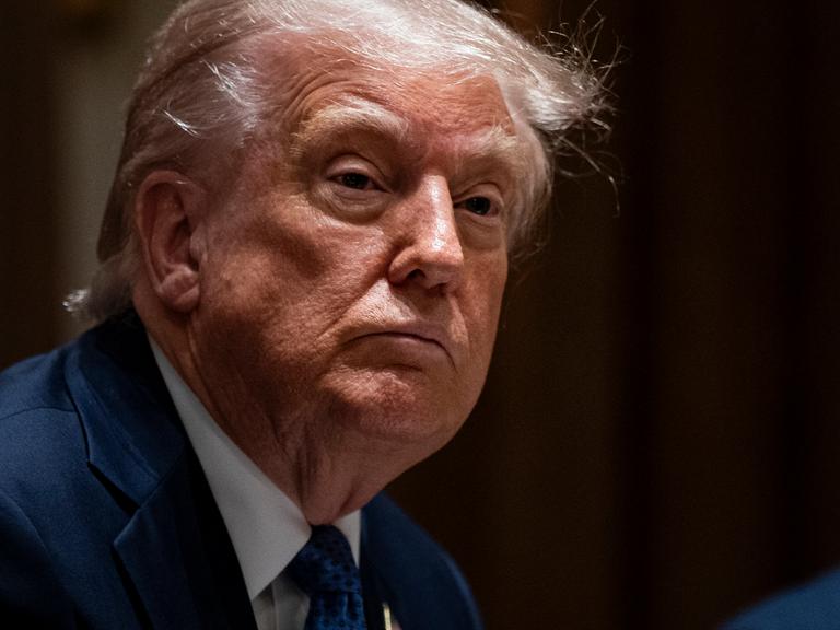 US-Präsident Donald Trump blickt in die Kamera vor einem schwarzen Hintergrund