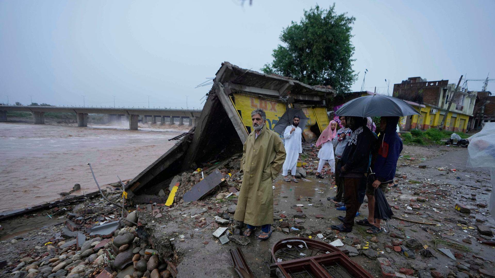 Anwohner betrachten die Überreste ihrer Häuser in Jammu, Indien, die durch Sturzfluten am Ufer des Tawi-Flusses beschädigt wurden. Anwohner betrachten die Überreste ihrer Häuser in Jammu, Indien, die durch Sturzfluten am Ufer des Tawi-Flusses beschädigt wurden.
