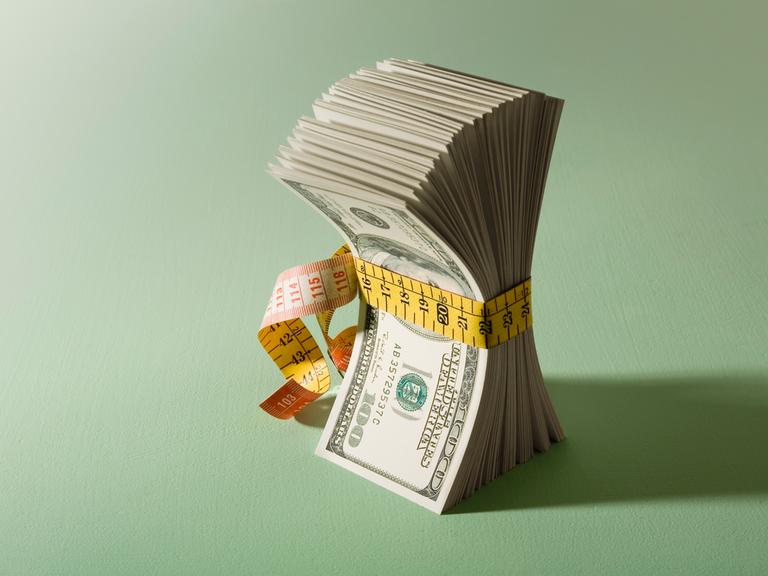 Illustration: Ein Bündel Dollarscheine, die mit einem Maßband zusammengehalten werden