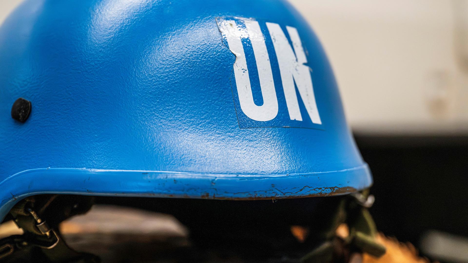 Ein leuchtend blauer Schutzhelm eines UNO-Soldaten liegt auf einem Tisch.