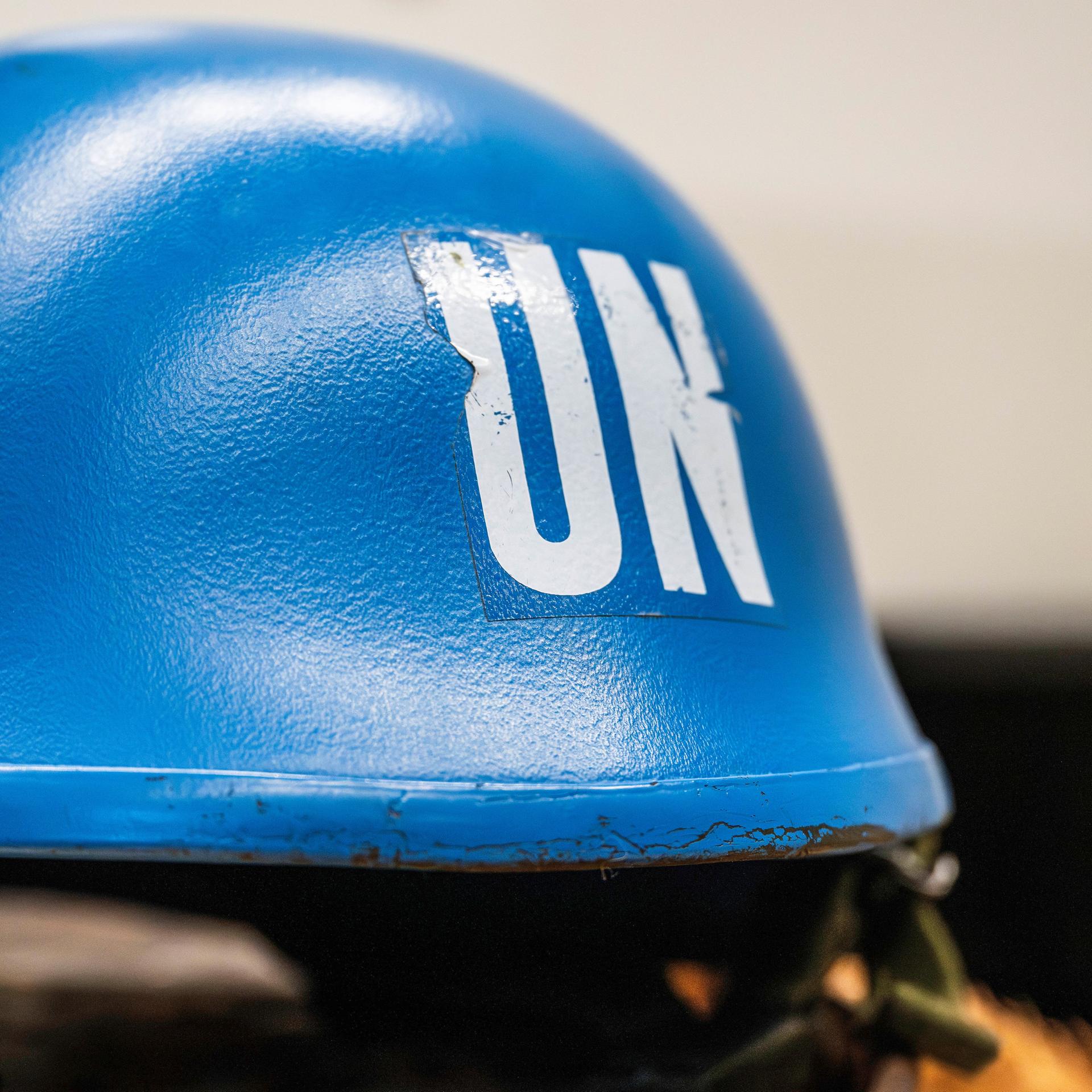 Ein leuchtend blauer Schutzhelm eines UNO-Soldaten liegt auf einem Tisch.