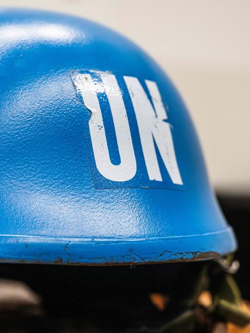 Ein leuchtend blauer Schutzhelm eines UNO-Soldaten liegt auf einem Tisch.