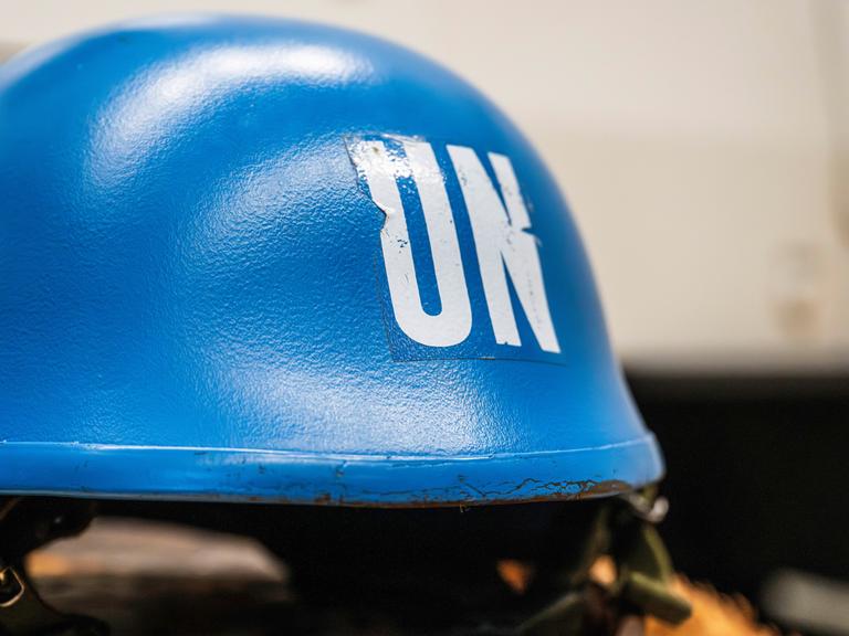 Ein leuchtend blauer Schutzhelm eines UNO-Soldaten liegt auf einem Tisch.