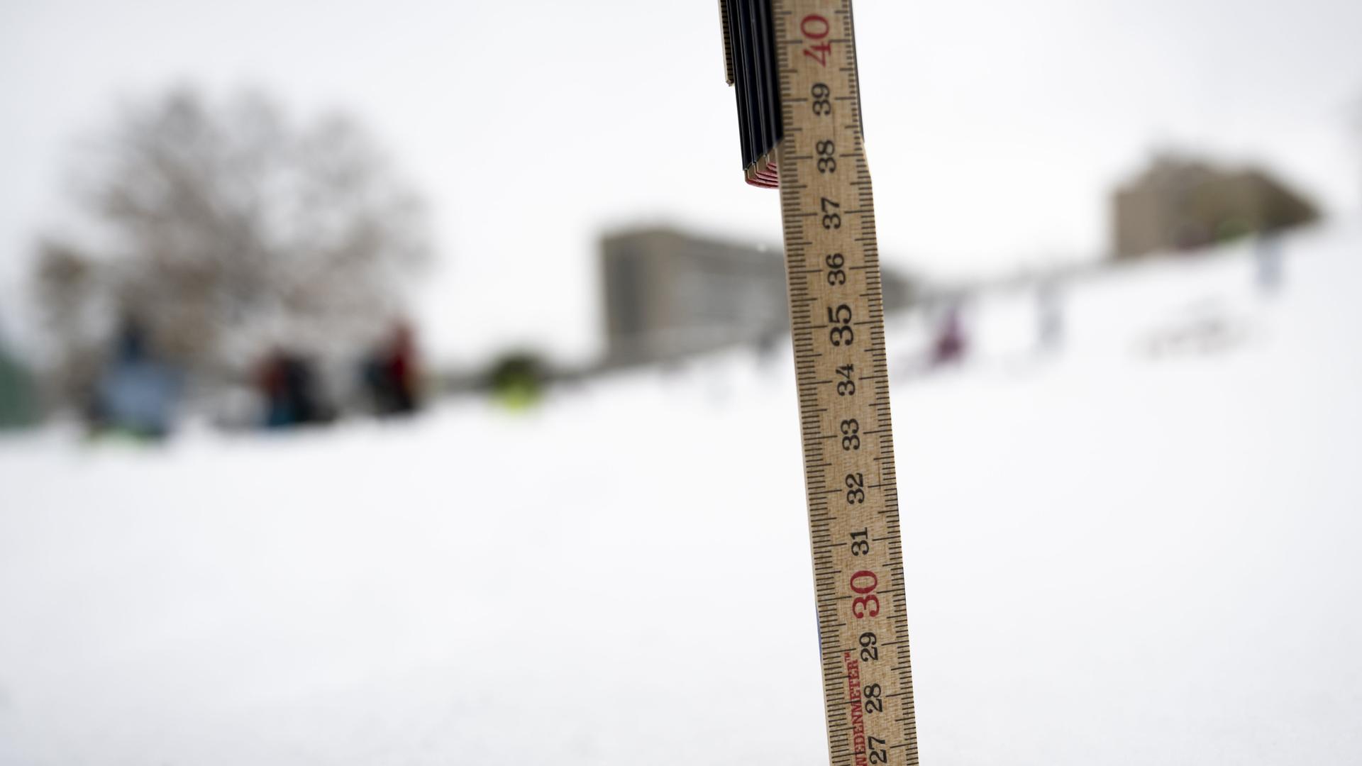 Ein Meterstab steckt im Schnee. 