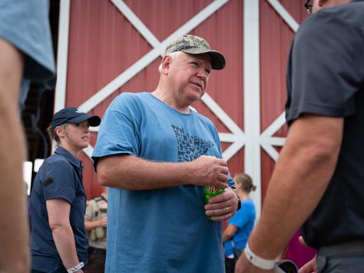 Tim Walz steht in Freizeitkleidung unter Wählern und unterhält sich mit ihnen.