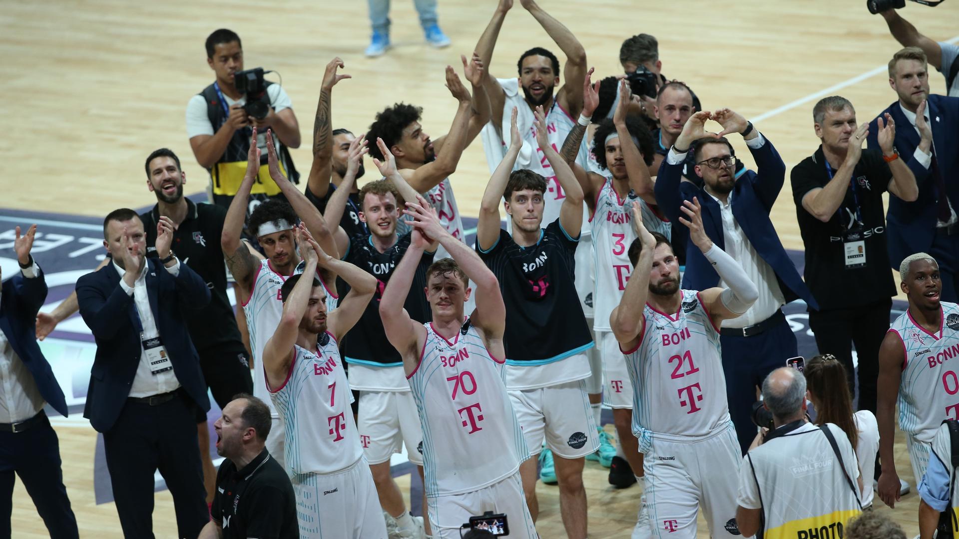 Die Bonner Basketballer feiern ihren Einzug ins Finale. Sie stehen zusammen in der Halle auf dem Platz und klatschen. Die Bonner Basketballer feiern ihren Einzug ins Finale. Sie stehen zusammen in der Halle auf dem Platz und klatschen.