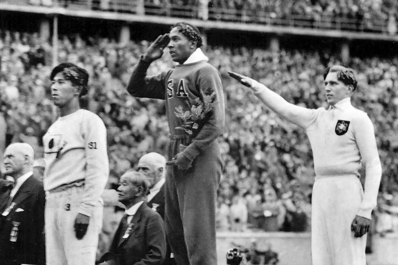 Jesse Owens (Mitte), Luz Long (rechts) und Naoto Tajima (links) bei der Siegerehrung bei den Olympischen Spielen in Berlin 1936