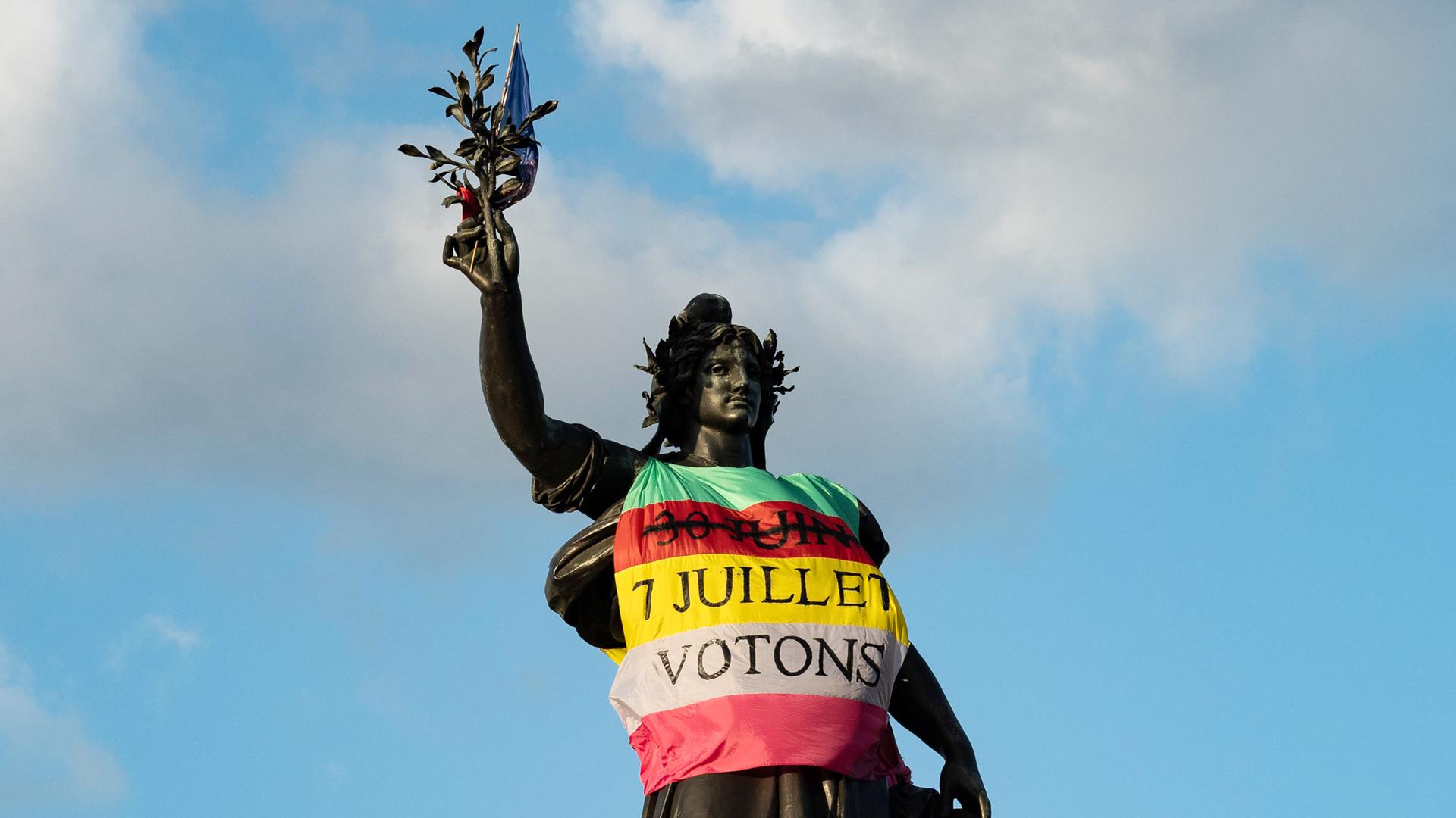 Fahne an der Marianne-Statue in Paris auf der Place de la Republique, in den Farben der neuen Volksfront Nouveau Front Populaire mit der Aufschrift "7. Juli, lasst uns wählen".