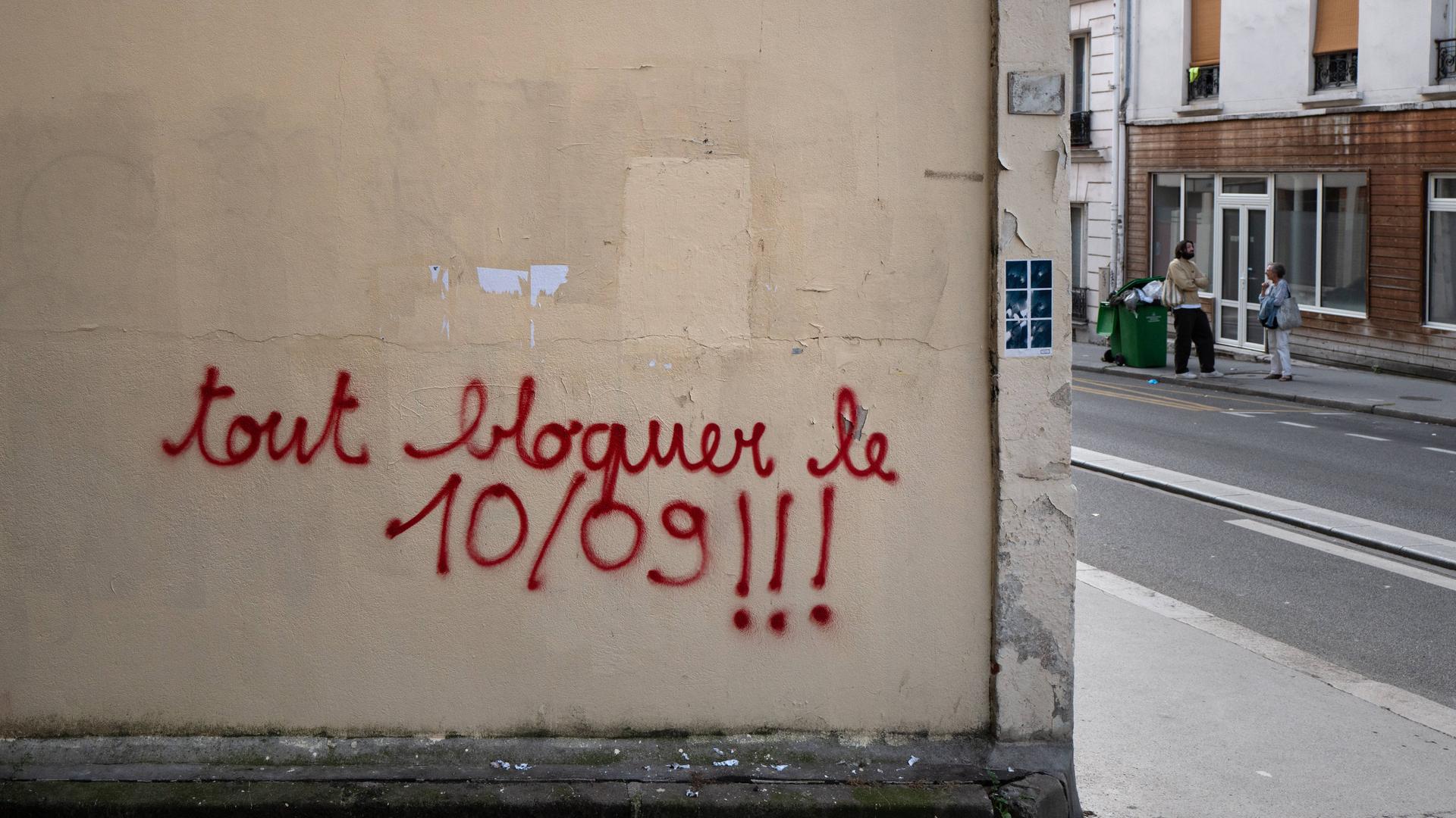 An einer Wand ist die Parole "bloquons tout" - zu deutsch "alles blockieren - mit Farbe gesprüht. 