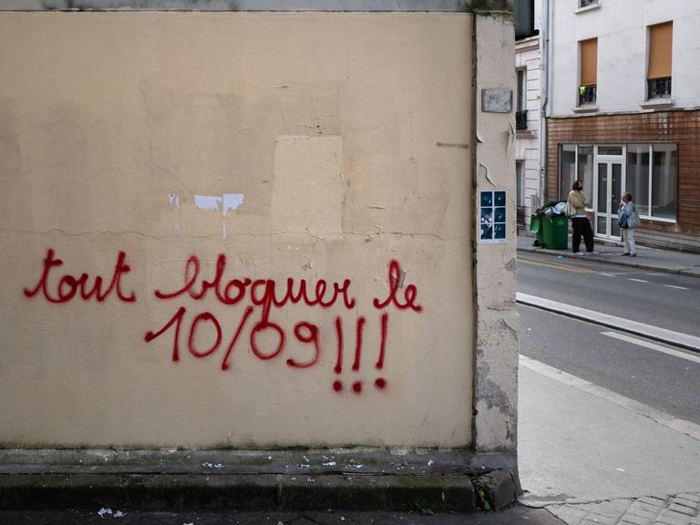 An einer Wand ist die Parole "bloquons tout" - zu deutsch "alles blockieren - mit Farbe gesprüht. 