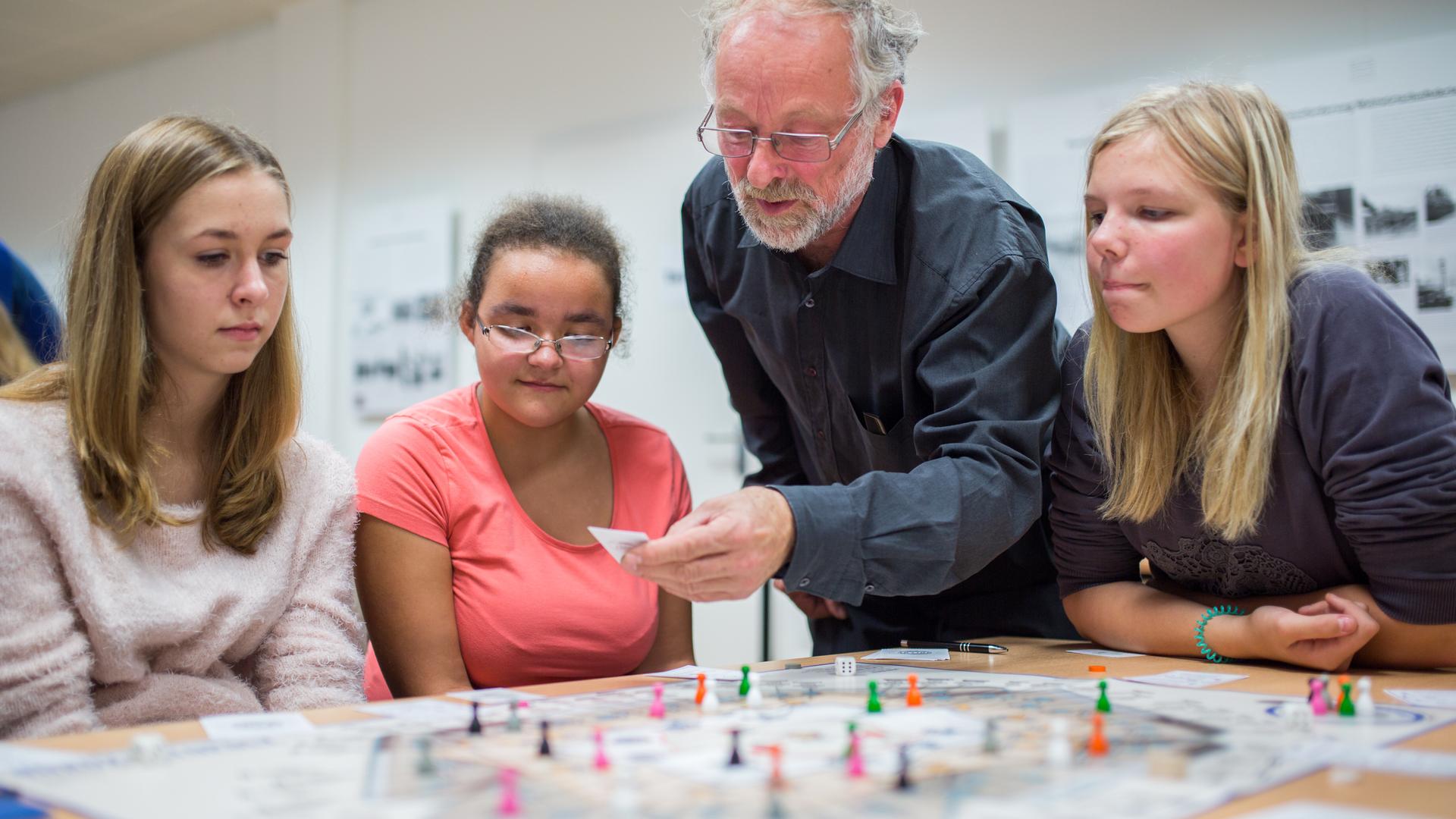 Martin Böttger (2.v.r.) erklärt Schülerinnen des Carl Bechstein Gymnasiums sein Spiel "Bürokratopoly" in Berlin, das die Realität des SED-Regimes näherbringen soll. Martin Böttger (2.v.r.) erklärt Schülerinnen des Carl Bechstein Gymnasiums sein Spiel "Bürokratopoly" in Berlin, das die Realität des SED-Regimes näherbringen soll.