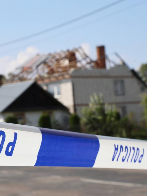 Hinter dem Absperrband der Polizei sieht man ein beschädigtes Haus in einem polnischen Dorf.