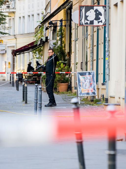 Polizeikräfte stehen vor einem Gebäude auf dem Gehweg.