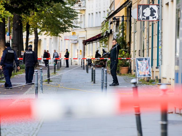 Polizeikräfte stehen vor einem Gebäude auf dem Gehweg.