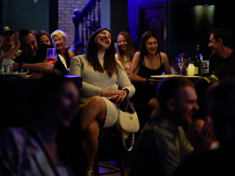 Lachende Menschen in einer Stand-up-Comedy-Show in Kiew im Juni 2022.