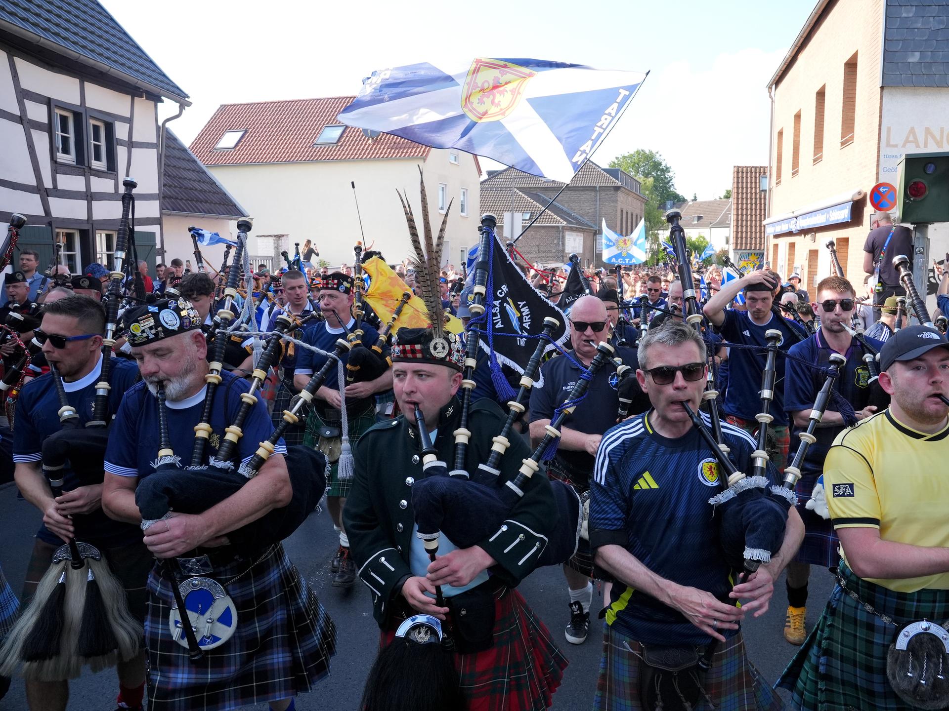 Männer in Kilts und Dudelsäcken laufen durch eine Strasse. Die „Tartan Army“ nimmt vor einem Fußballspiel im Kölner Stadion an einem organisierten Marsch zum Stadion teil. 