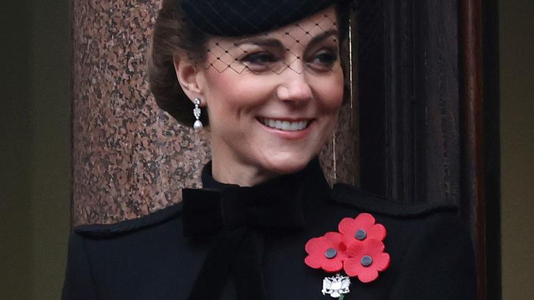 Die Prinzessin Kate trägt ein schwarzes Kleid. Das Kleid ist mit einer Mohn-Blume dekoriert. Die Prinzessin Kate trägt ein schwarzes Kleid. Das Kleid ist mit einer Mohn-Blume dekoriert.