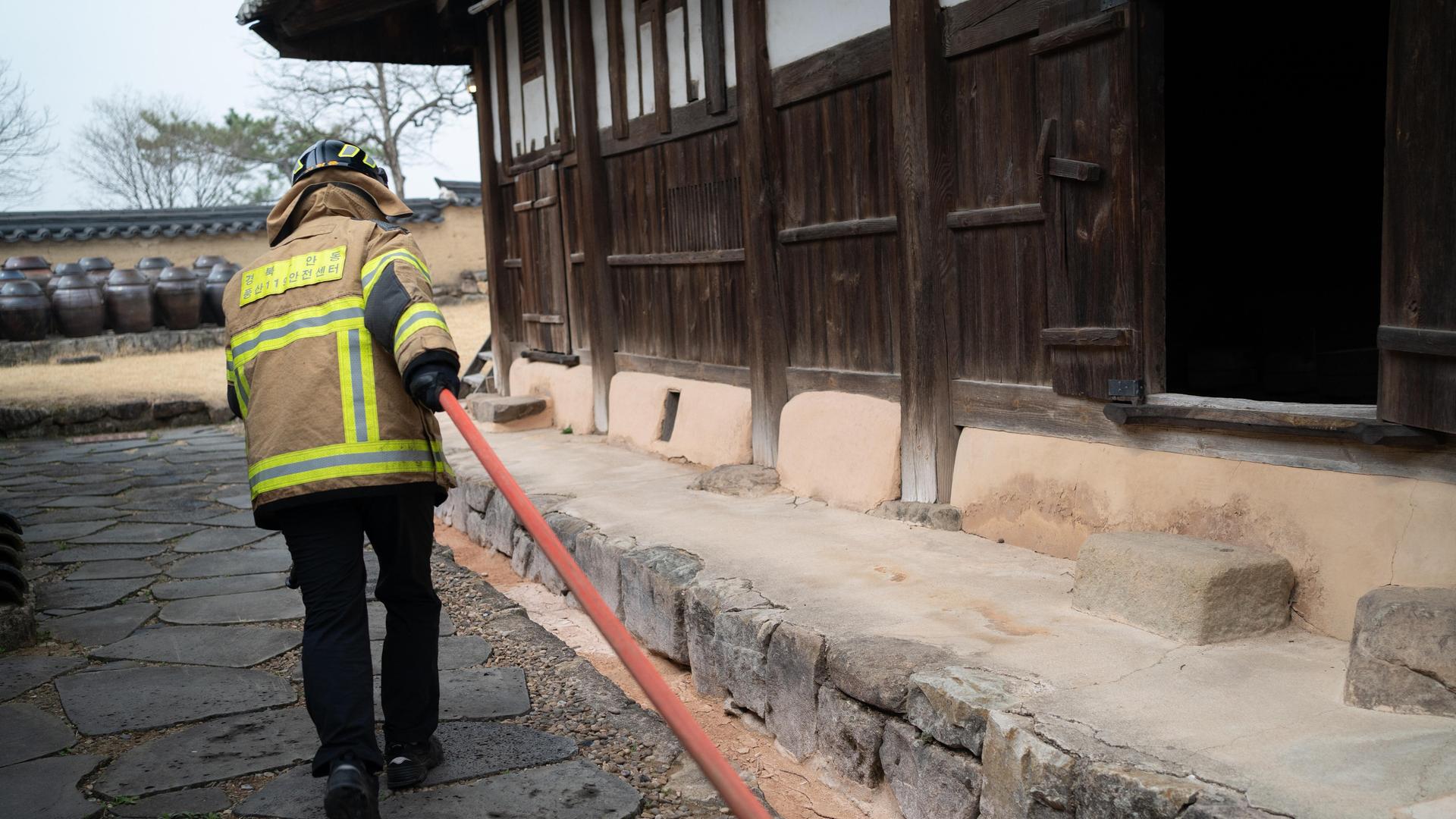 Feuerwehrleute verteilen Wasser, um das Feuer im Dorf Hahoe, das zum UNESCO-Weltkulturerbe gehört, einzudämmen. Das Feuer breitet sich bei starkem Wind in Andong aus. Feuerwehrleute verteilen Wasser, um das Feuer im Dorf Hahoe, das zum UNESCO-Weltkulturerbe gehört, einzudämmen. Das Feuer breitet sich bei starkem Wind in Andong aus.