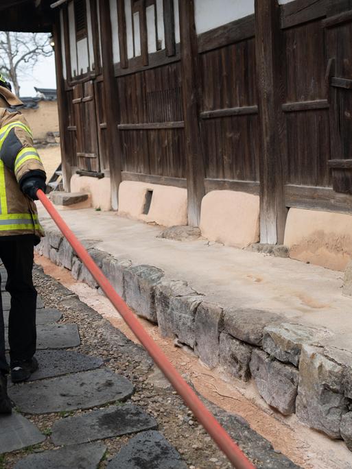 Feuerwehrleute verteilen Wasser, um das Feuer im Dorf Hahoe, das zum UNESCO-Weltkulturerbe gehört, einzudämmen. Das Feuer breitet sich bei starkem Wind in Andong aus.