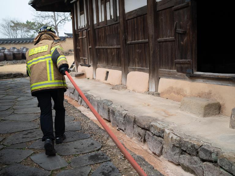 Feuerwehrleute verteilen Wasser, um das Feuer im Dorf Hahoe, das zum UNESCO-Weltkulturerbe gehört, einzudämmen. Das Feuer breitet sich bei starkem Wind in Andong aus.
