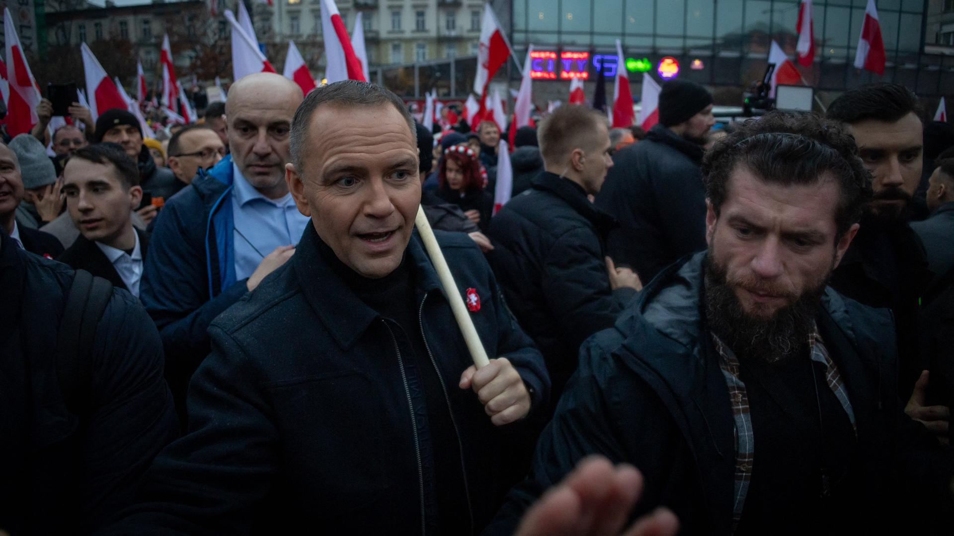 Polens Präsident Nawrocki nimmt an einer Kundgebung teil und trägt eine polnische Flagge in seiner linken Hand. 