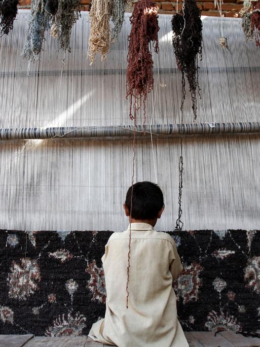 Ein zwölfjährige Junge webt im Umkreis von Afghanistans Hauptstadt Kabul einen Teppich. Mit dem Einkommen aus der Arbeit unterstützt er seine Familie. 