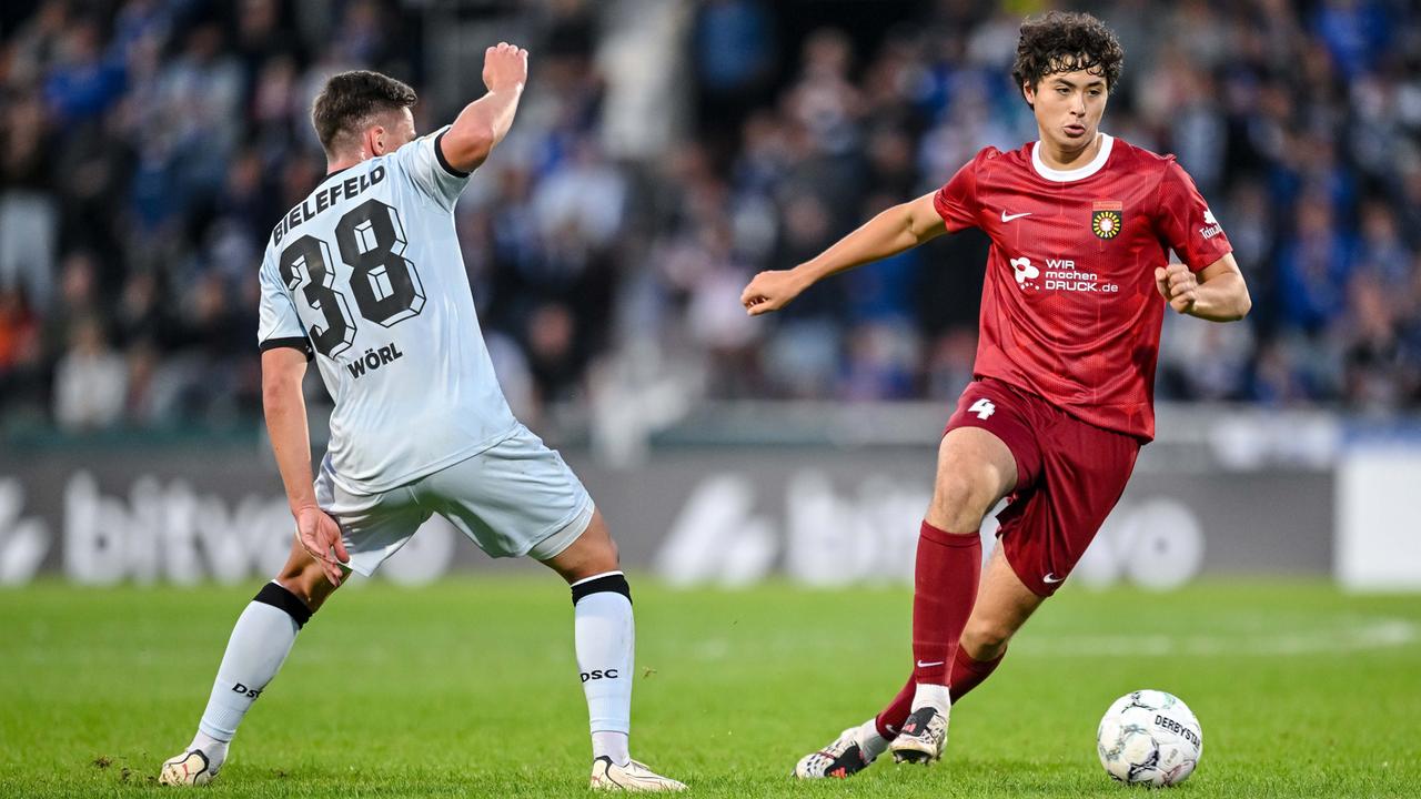 Marius Woerl im weißen Trikot von Arminia Bielefeld und Franz Bleicher im roten Trikot von Sonnenhof Großaspach kämpfen um den Ball.
