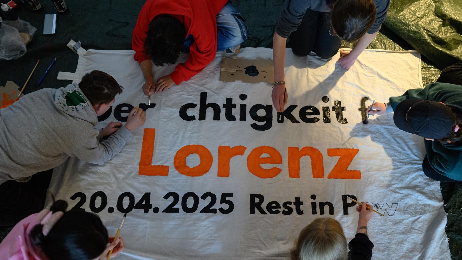 Mehrere Personen beschriften ein Transparent mit dem Schriftzug „Gerechtigkeit für Lorenz“. Mehrere Personen beschriften ein Transparent mit dem Schriftzug „Gerechtigkeit für Lorenz“.