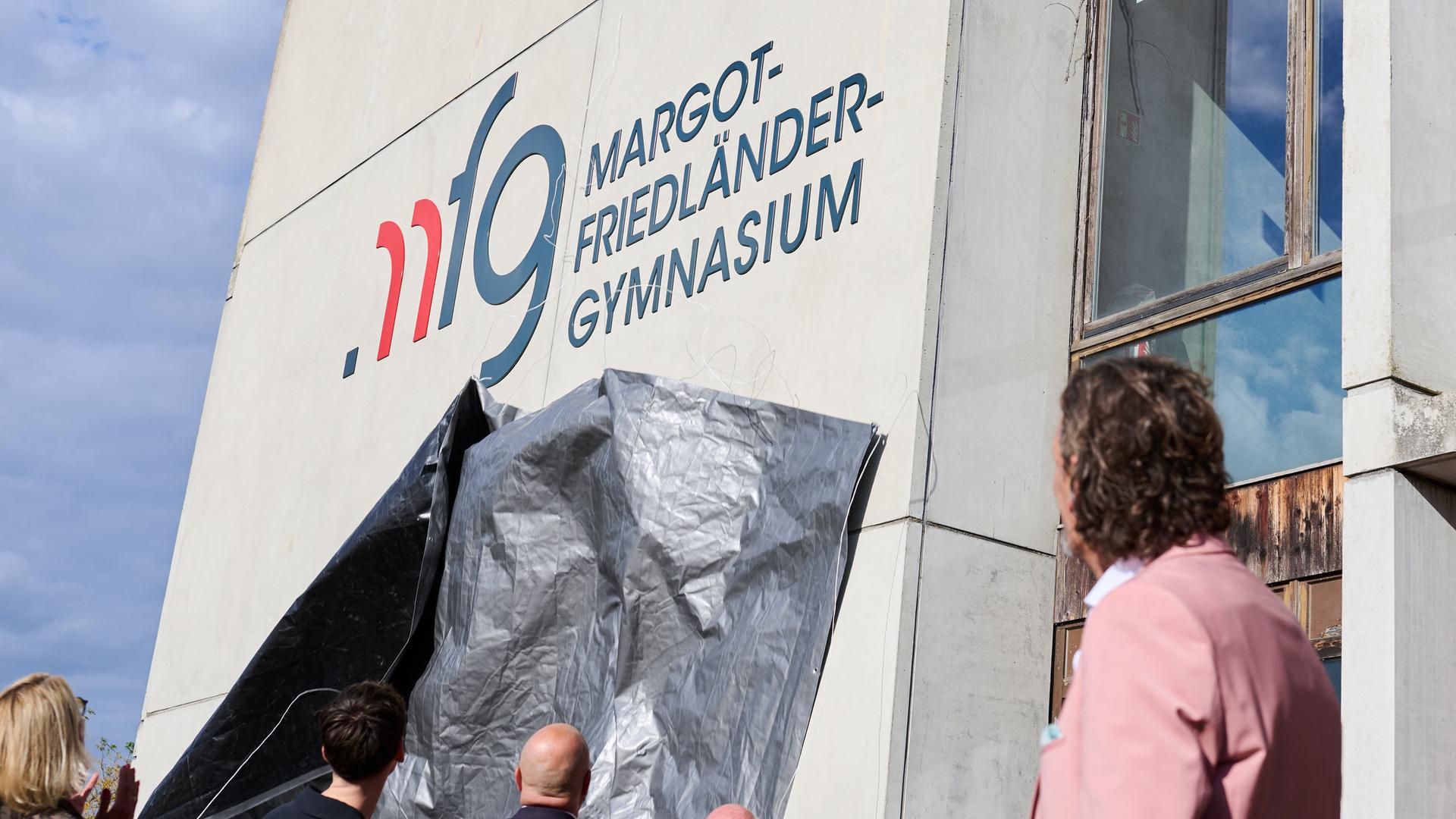 An der Fassade einer Schule steht "Margot-Friedländer-Gymnasium". An der Fassade einer Schule steht "Margot-Friedländer-Gymnasium".