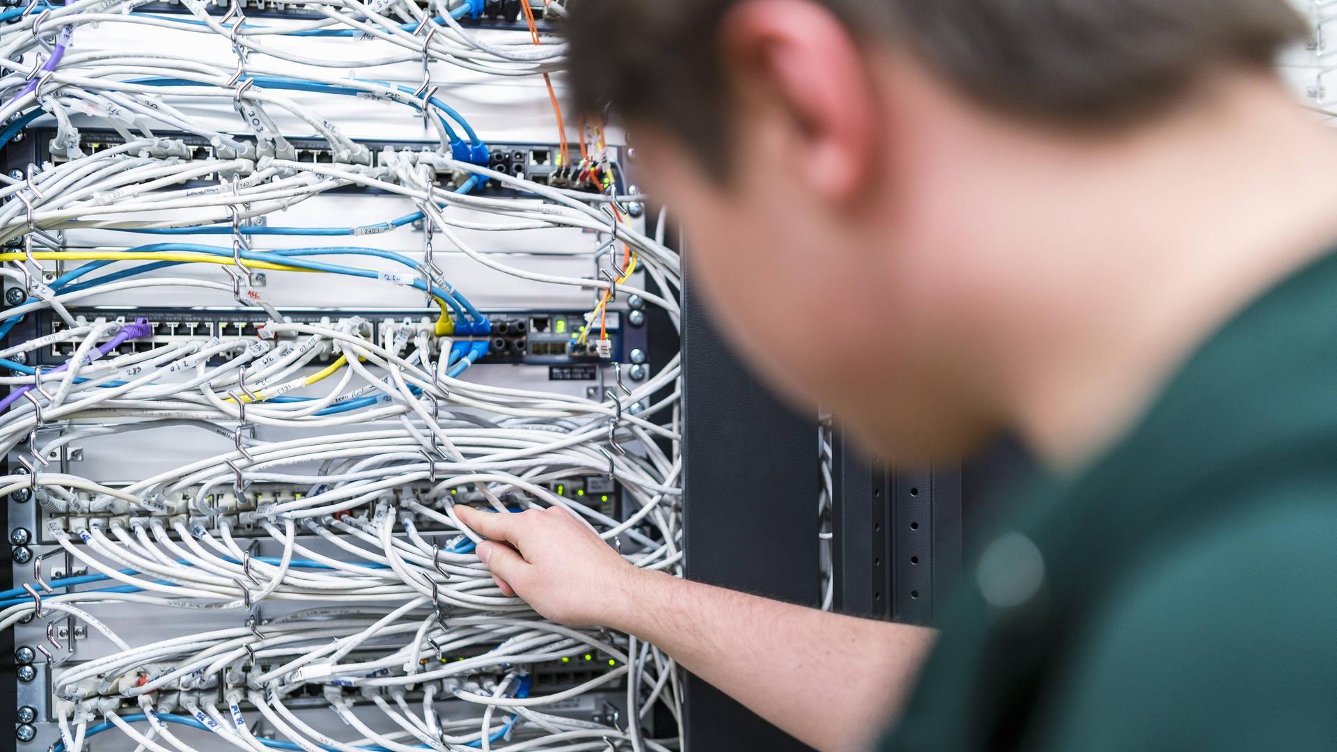 Ein Jugendlicher arbeitet an Kabeln in einem Serverraum