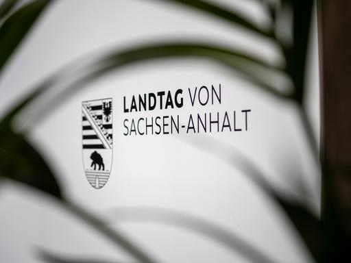 Das Logo des Landtags von Sachsen-Anhalt ist auf einem Schild zu sehen. Unscharfe Blätter im Vordergrund verdecken das Schild teilweise und bilden einen Rahmen um die Aufnahme. (Symbolbild) Das Logo des Landtags von Sachsen-Anhalt ist auf einem Schild zu sehen. Unscharfe Blätter im Vordergrund verdecken das Schild teilweise und bilden einen Rahmen um die Aufnahme. (Symbolbild)