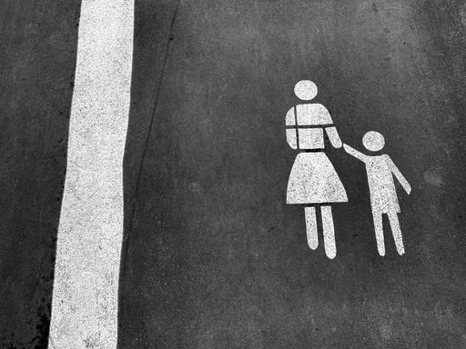 Darstellung von Mutter mit Kind an der Hand als Markierung auf dem Straßenpflaster