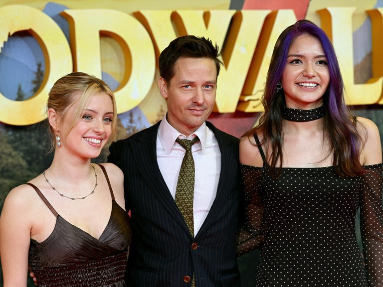 Der Schauspieler Tom Schilling posiert bei der Premiere von "Woodwalkers 2" im Mathäser Filmpalast mit den beiden Schauspielerinnen Lara Amelie Rosa (l) und Olivia Sinclair.