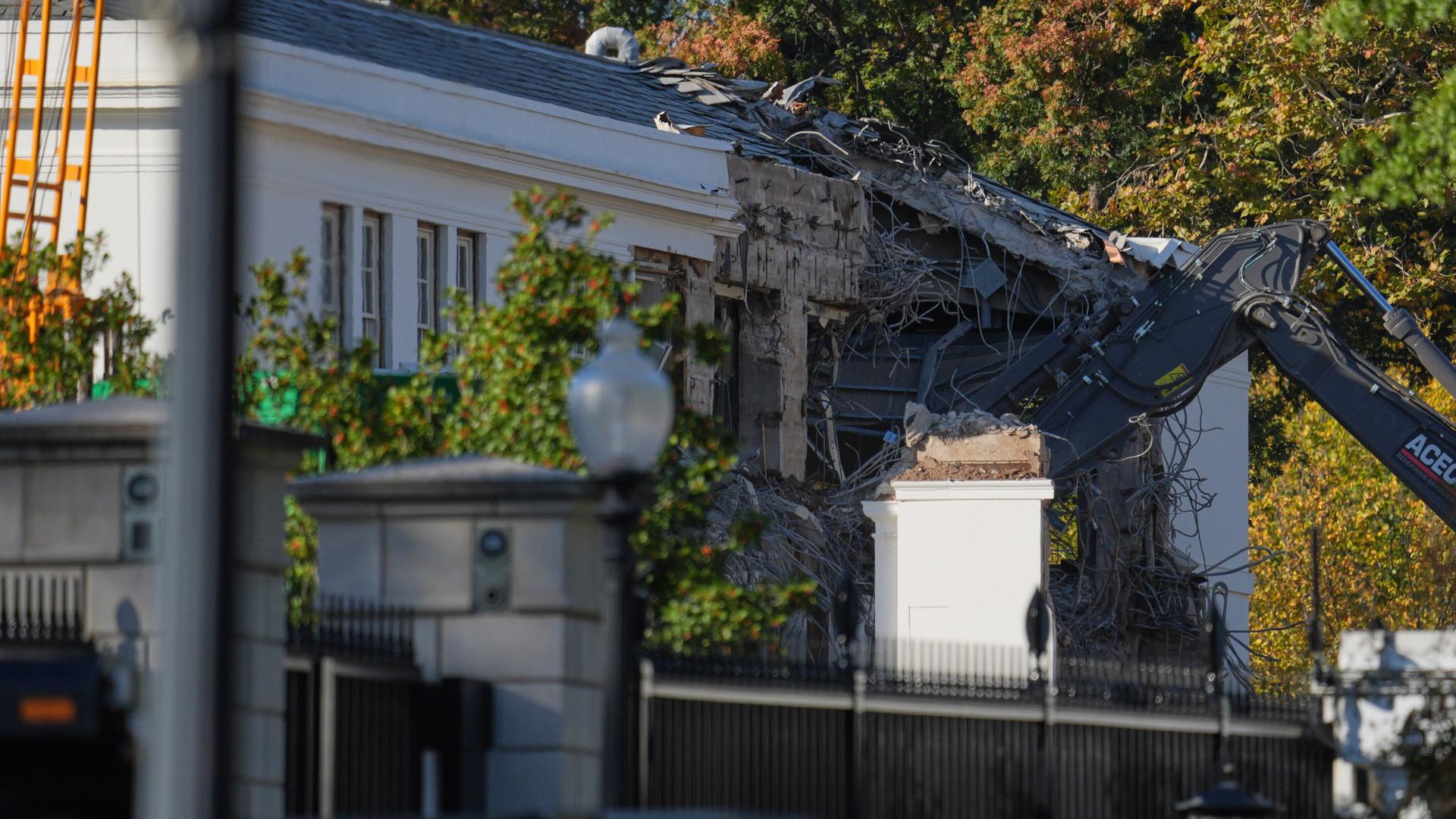 Ein Bagger reißt die Wand eines Gebäudes ein, das zum Weißen Haus gehört. Ein Bagger reißt die Wand eines Gebäudes ein, das zum Weißen Haus gehört.