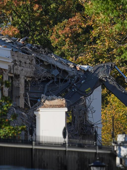 Ein Bagger reißt die Wand eines Gebäudes ein, das zum Weißen Haus gehört.