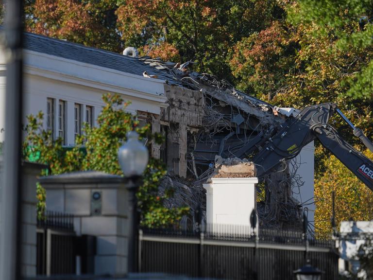 Ein Bagger reißt die Wand eines Gebäudes ein, das zum Weißen Haus gehört.