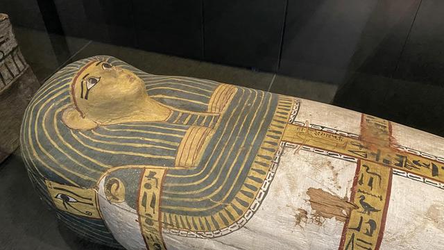 Ein ägyptischer Sarkophag ist bunt bemalt mit einem Gesicht und Schrift-Zeichen.