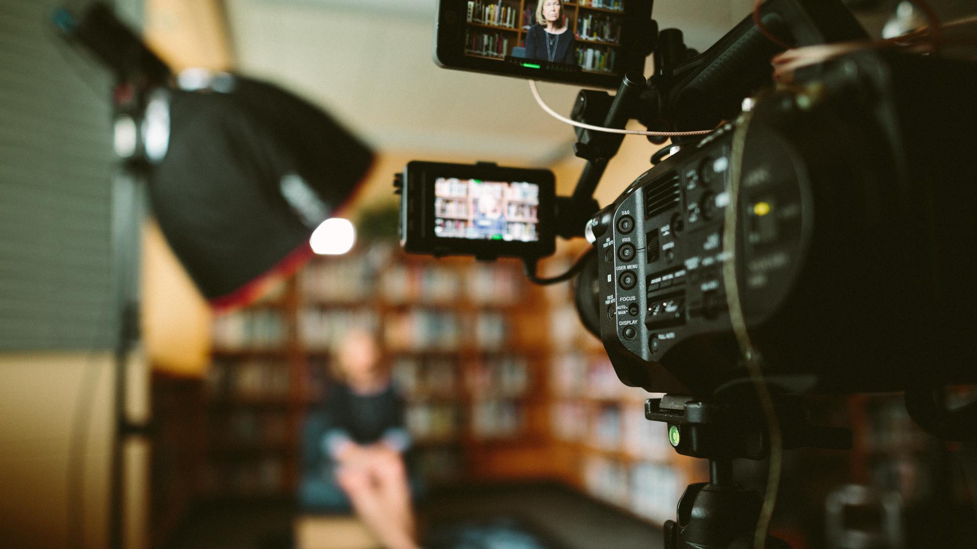 Großaufnahme einer Filmkamera, die ein im Unschärfebereich liegendes Set fotografiert