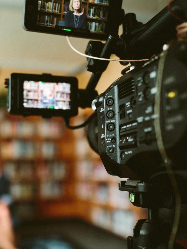 Großaufnahme einer Filmkamera, die ein im Unschärfebereich liegendes Set fotografiert