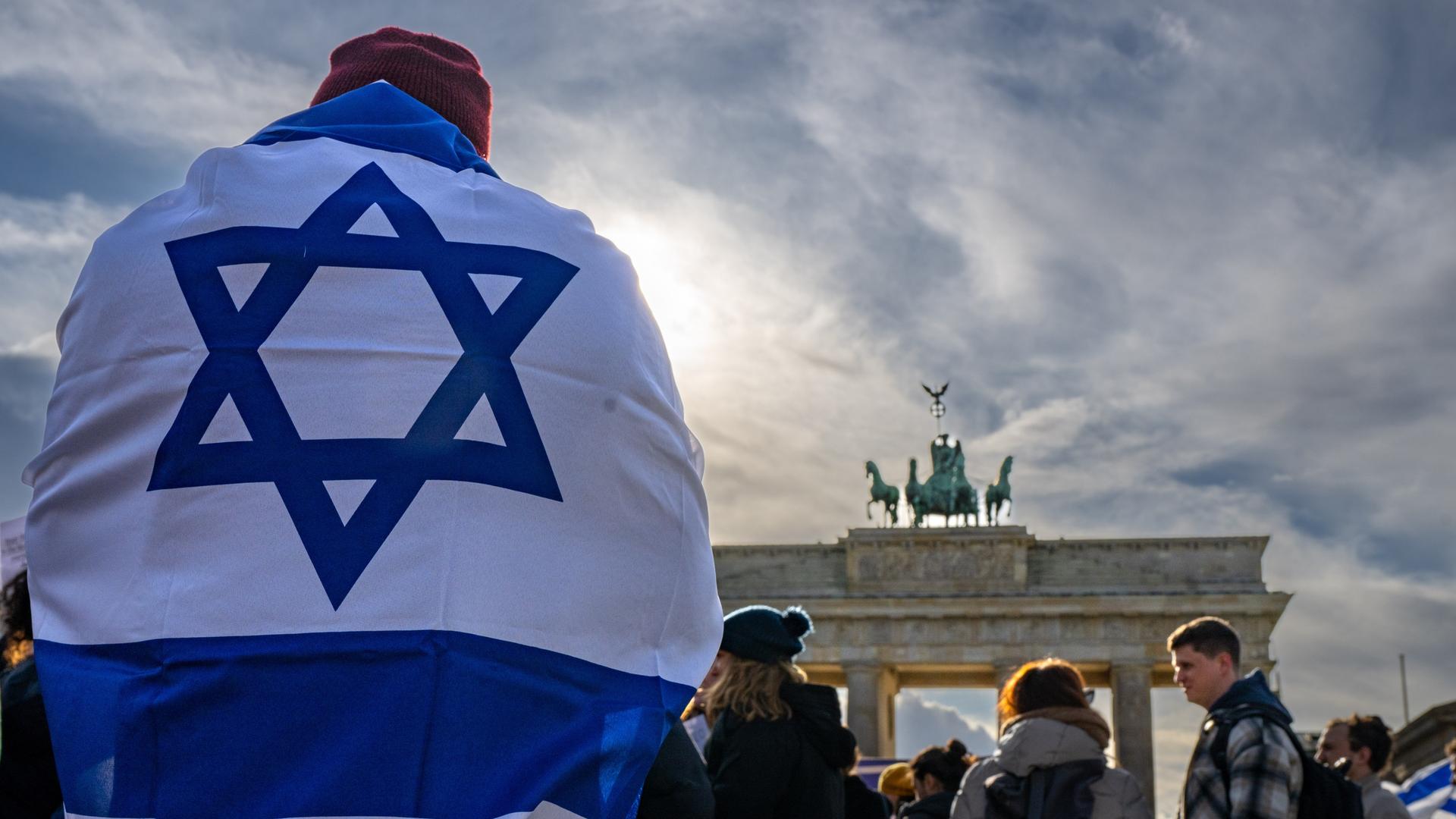 Ein Demonstrant trägt die israelische Nationalflagge auf dem Rücken bei einer Protestkundgebung gegen die umstrittene Justizreform in Israel vor dem Brandenburger Tor, 27. März 2023