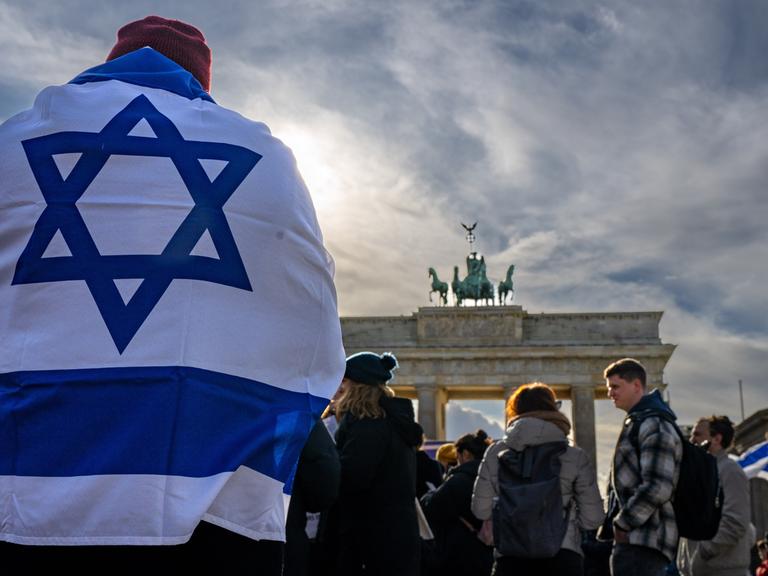 Ein Demonstrant trägt die israelische Nationalflagge auf dem Rücken bei einer Protestkundgebung gegen die umstrittene Justizreform in Israel vor dem Brandenburger Tor, 27. März 2023