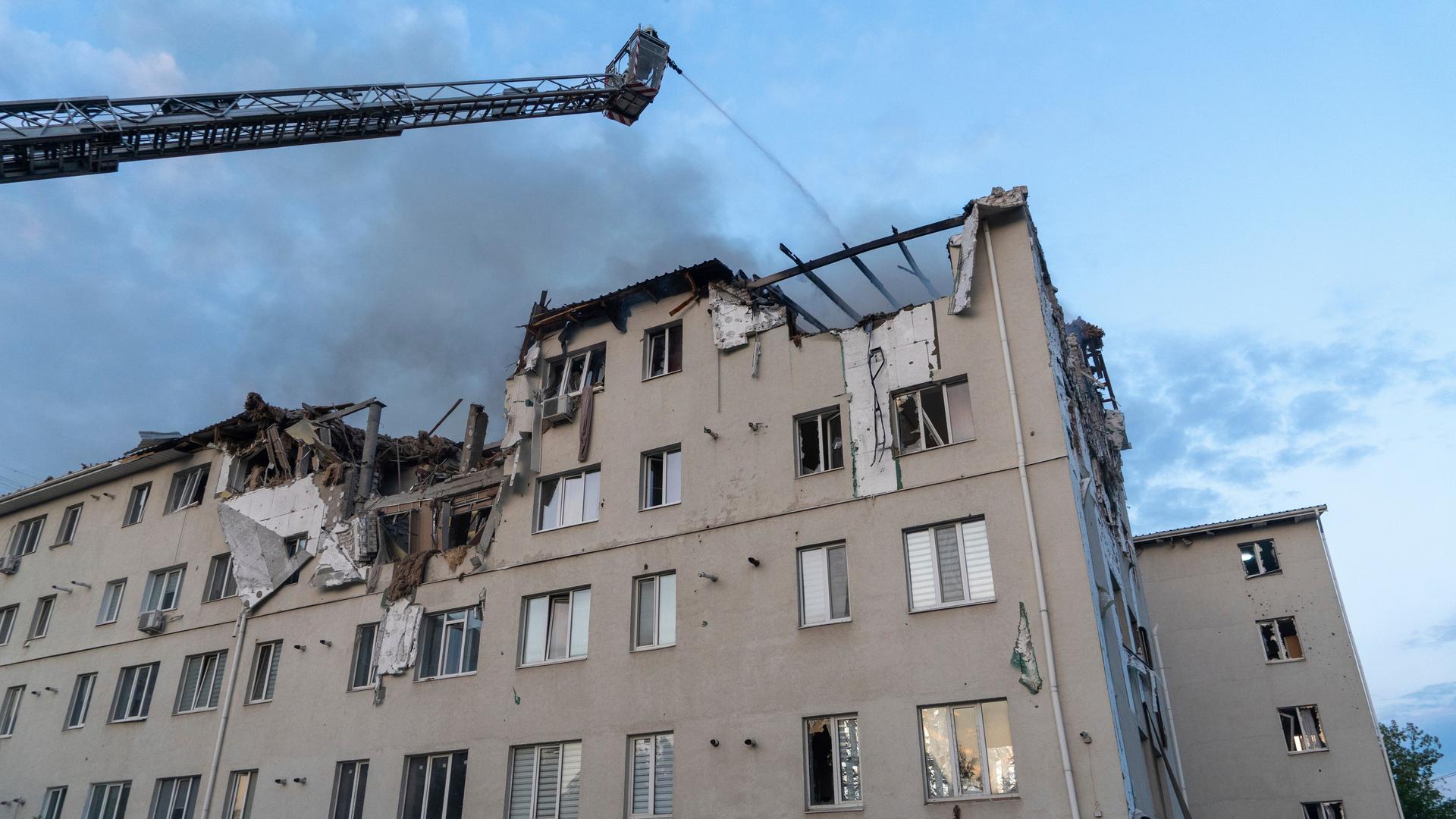 Ein mehrstöckiges Haus, das von einer russischen Rakete getroffen wurde, die Feuerwehr versucht zu löschen.