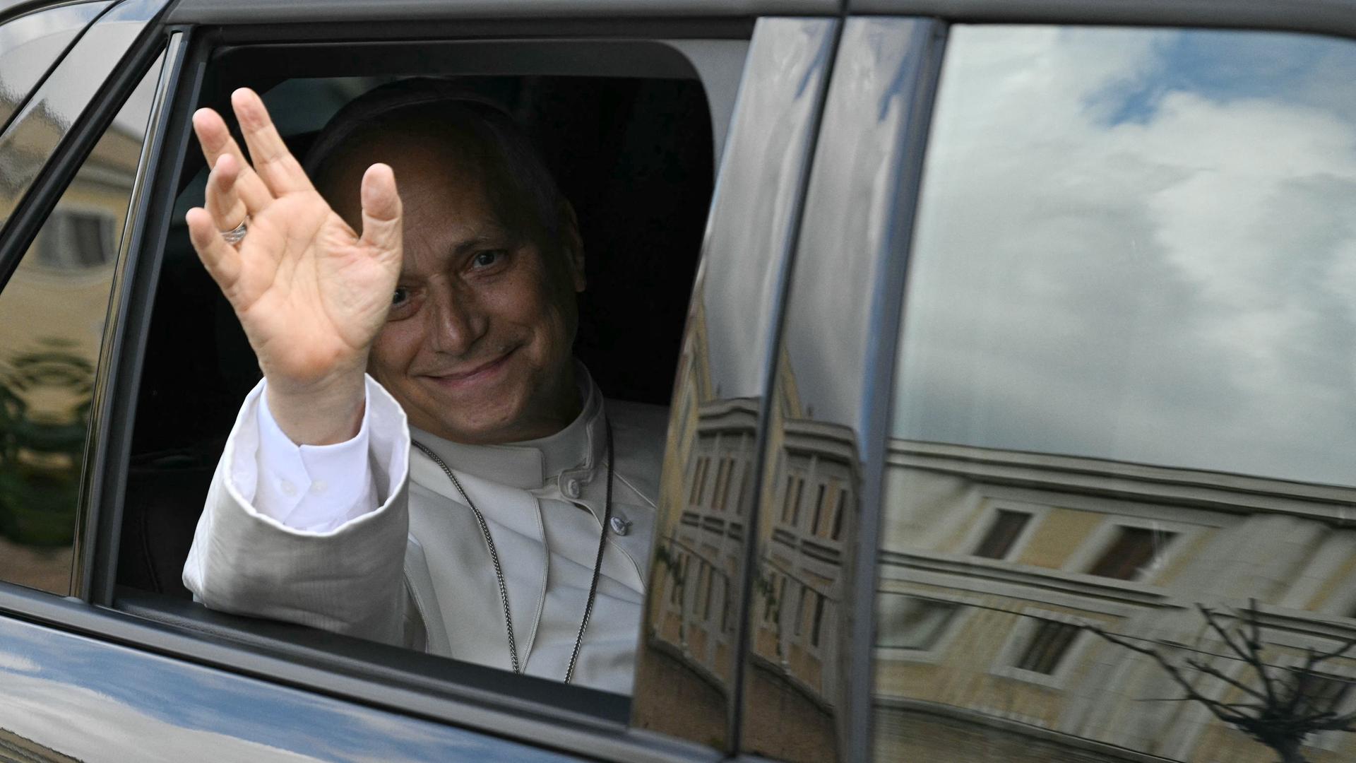 Papst Leo sitzt grüßend in einem Auto, das ihn nach überstandener Krebsoperation zurück in den Vatikan bringt. 
