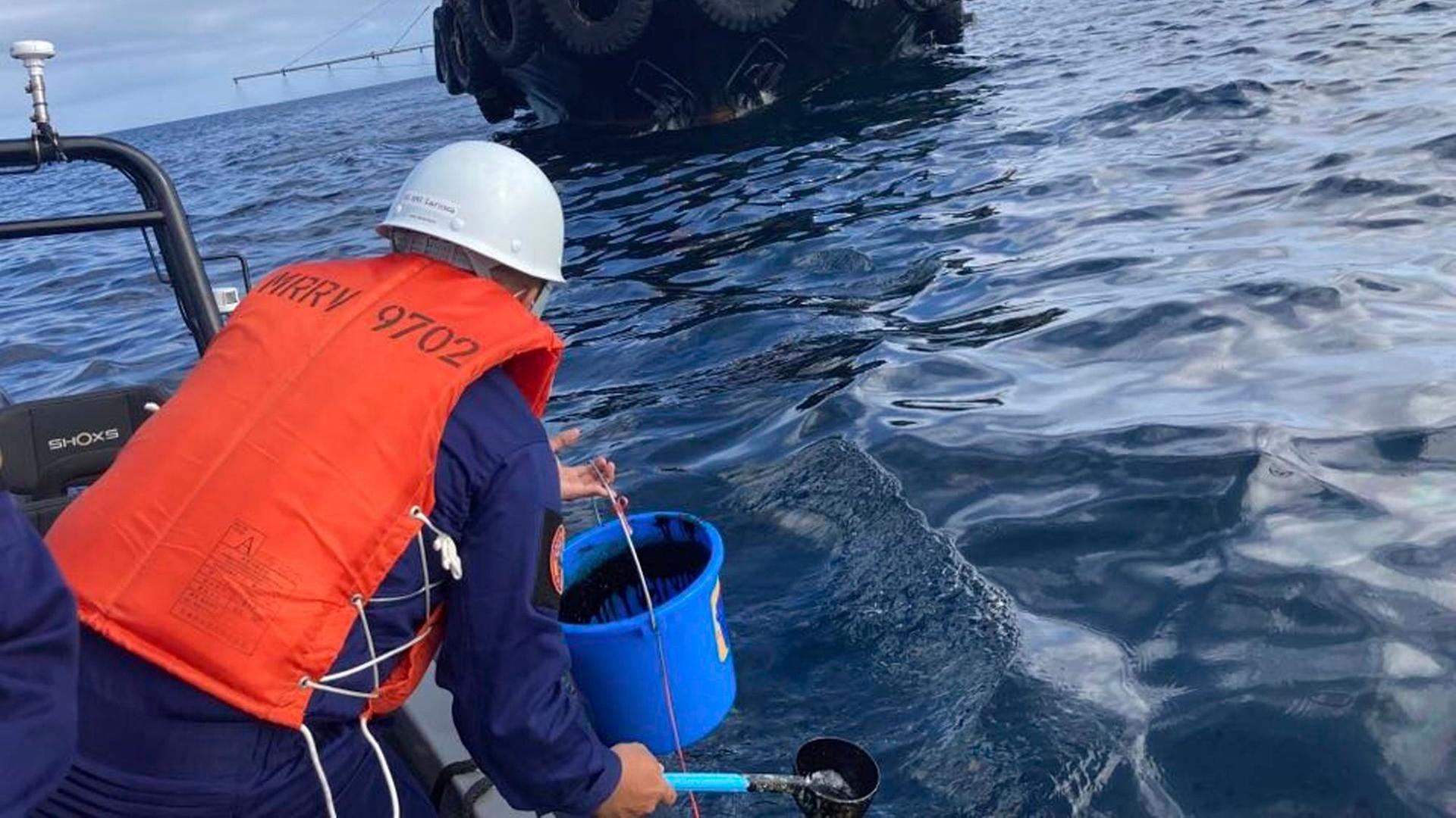 Philippinen, Manila: Ein Mitarbeiter der Küstenwache bei der Entnahme von Wasserproben, nachdem ein vor der Küste gesunkener Tanker Öl verliert. Der Tanker "MT Princess Empress" ist am 28.03.2023 vor der Küste gesunken. Philippinen, Manila: Ein Mitarbeiter der Küstenwache bei der Entnahme von Wasserproben, nachdem ein vor der Küste gesunkener Tanker Öl verliert. Der Tanker "MT Princess Empress" ist am 28.03.2023 vor der Küste gesunken.